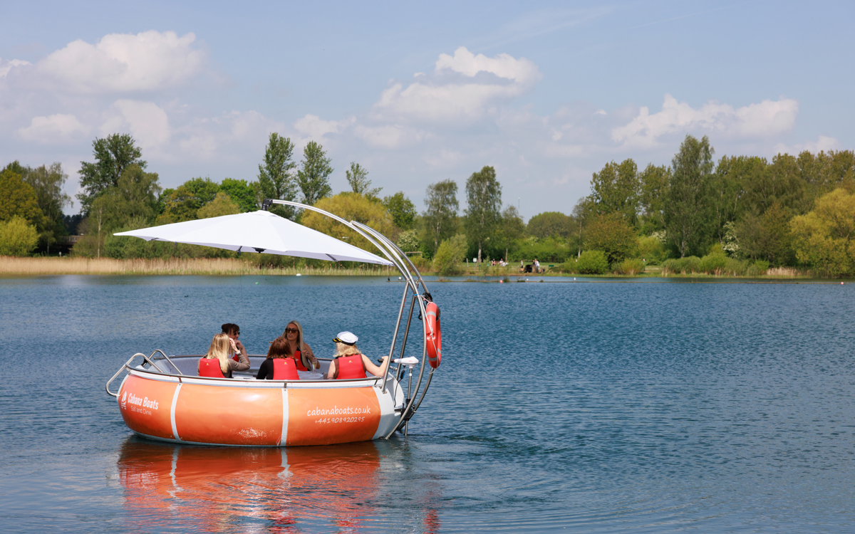 Cabana Boat floating on Willen Lake with trees in background