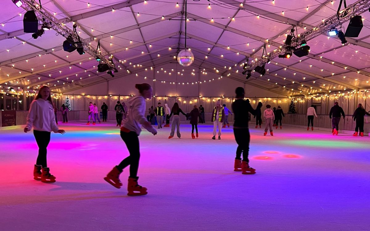 People ice skating on rink with disco ball