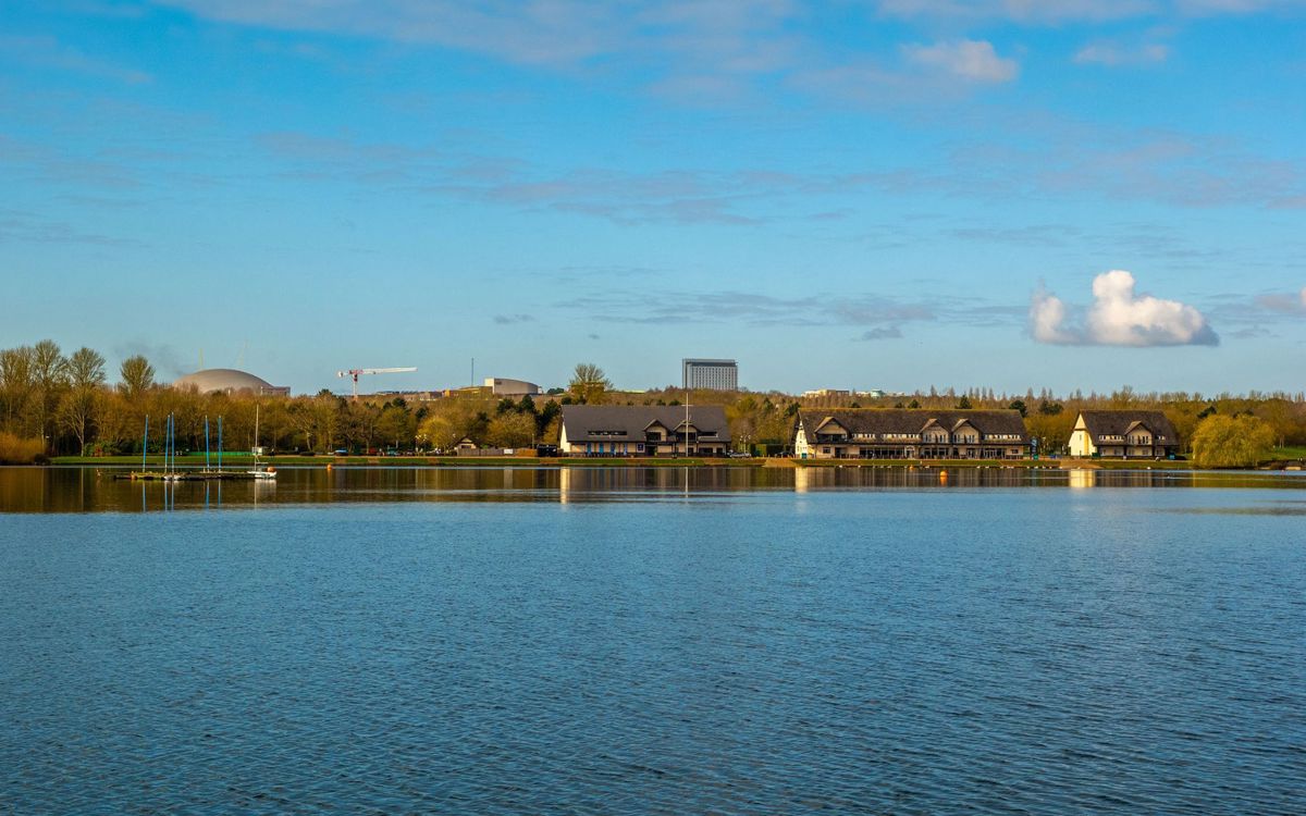 View across the lake with pub and Milton Keynes city centre landmarks in the distance