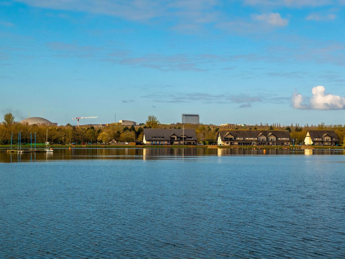 View across the lake with pub and Milton Keynes city centre landmarks in the distance