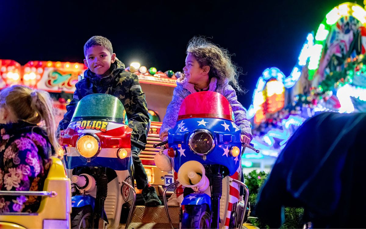Children enjoying fun fair ride on mini motorbikes