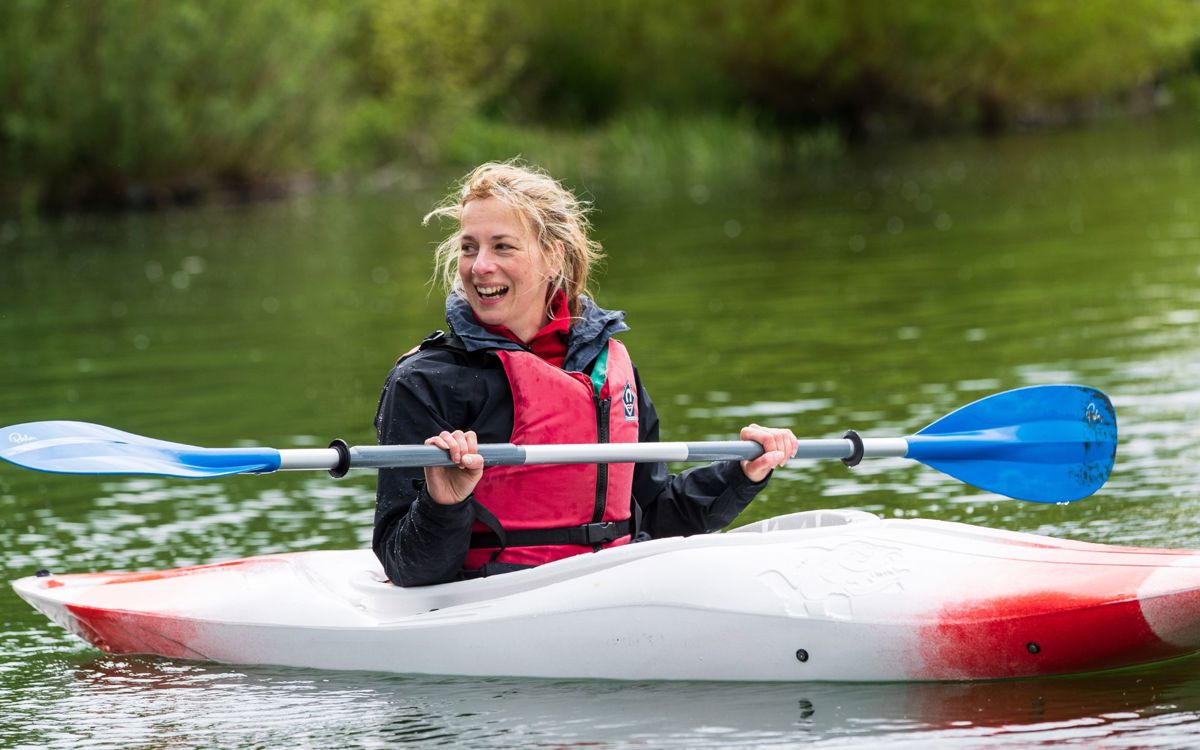 Person in red kayak holding paddle out of the water
