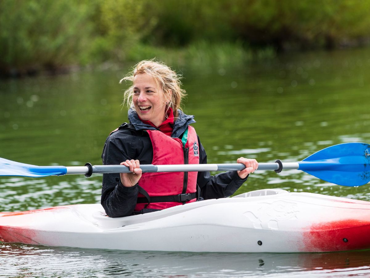 Person in red kayak holding paddle out of the water