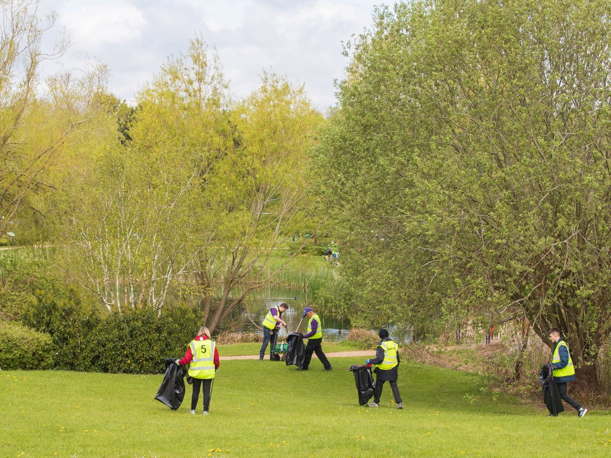 A group of hivis wearing litter pickers in a parkland scene