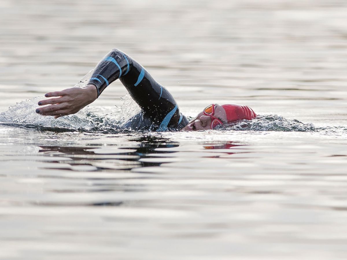 Person swimming in wetsuit and cap swimming in the lake