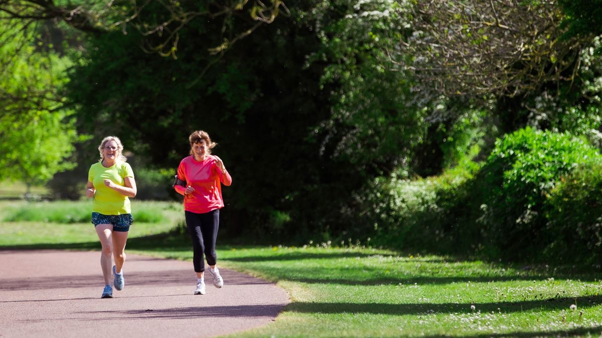 Two people running along Willen Lake path 