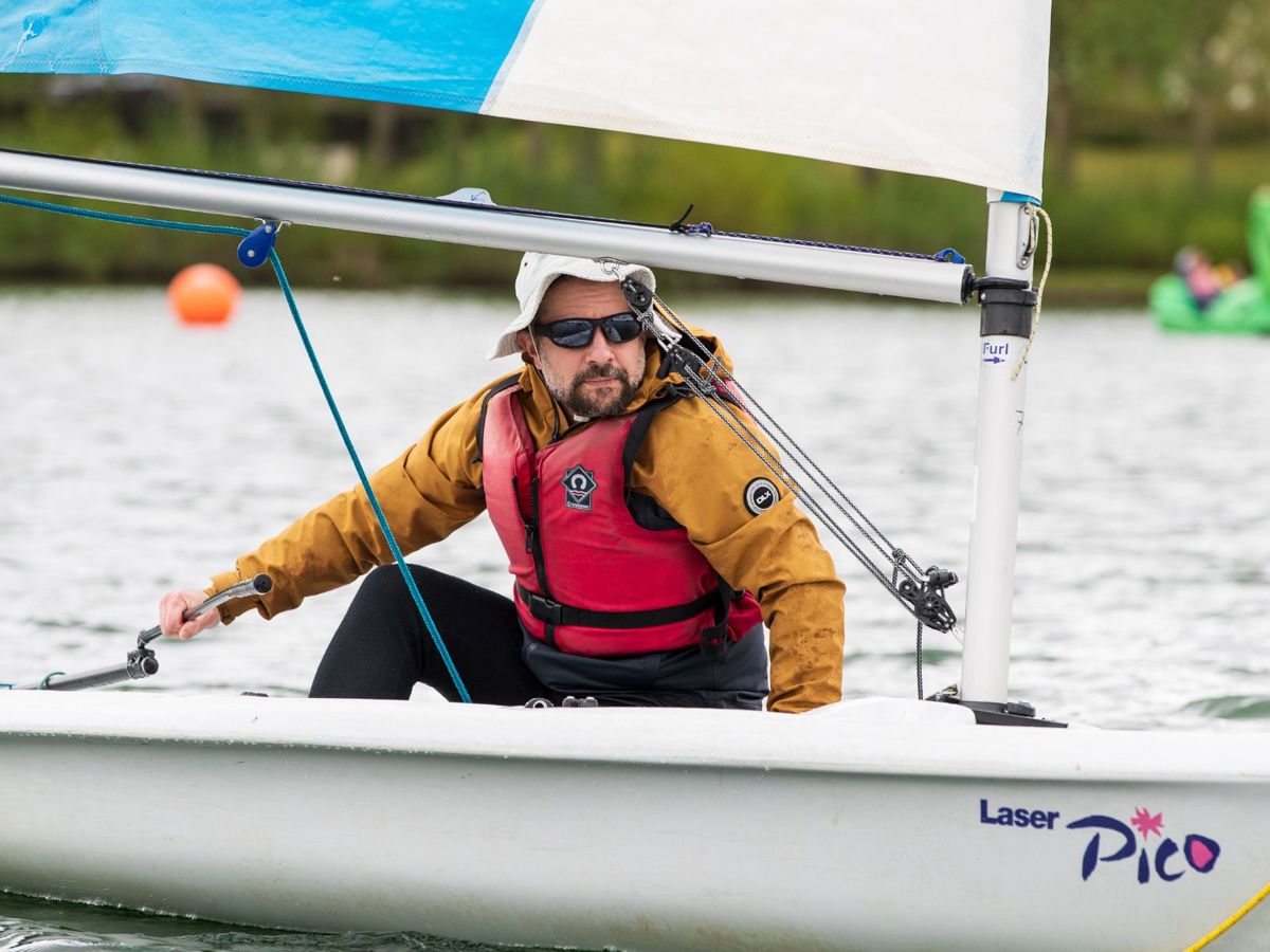Person navigating sailing boat on a lake