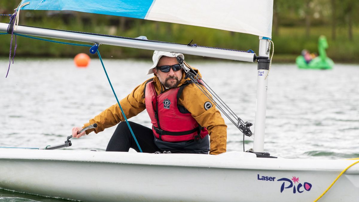 Person navigating sailing boat on a lake