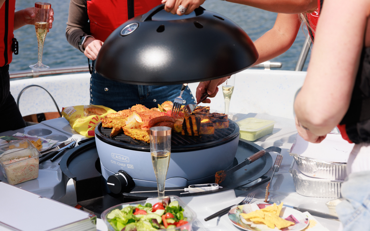 Person pulling lid of BBQ with food on