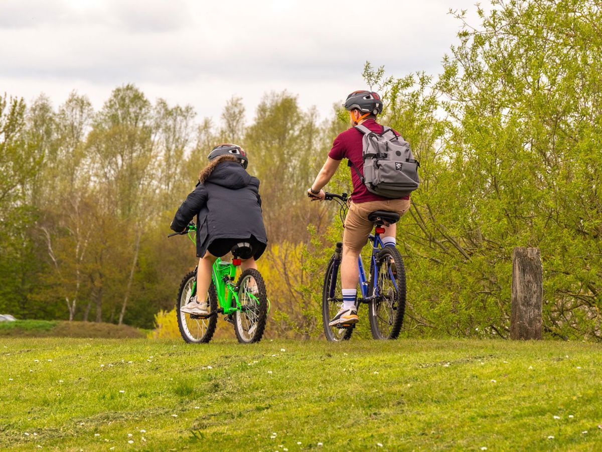 Two people cycling around Willen Lake with trees in the background