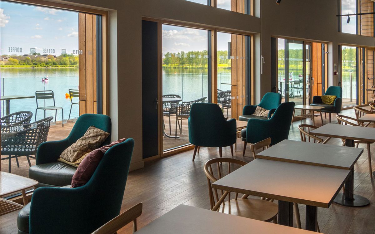 Inside of Willen Lake cafe showing tables and chairs and view across the lake