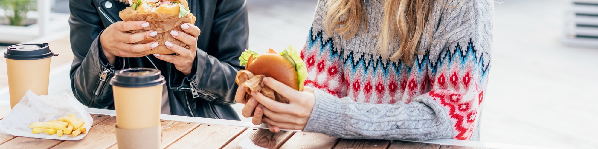 Two people sat at a table eating a burger at a street food event