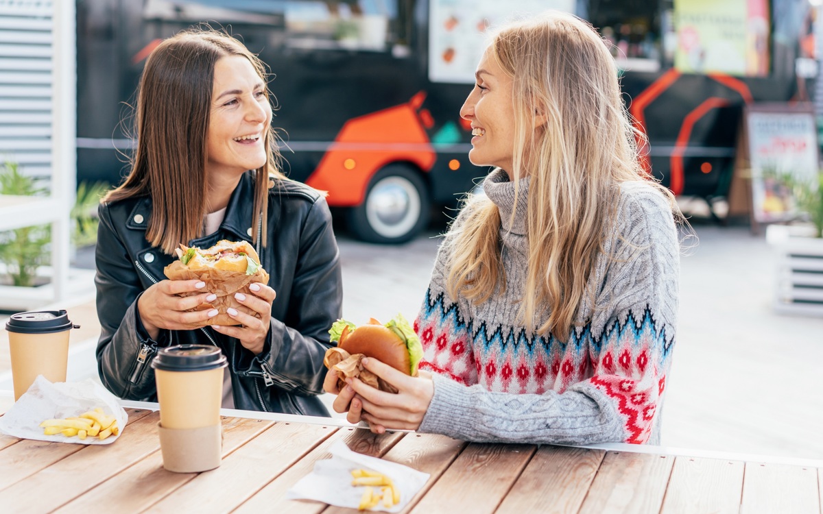 Two people sat at a table eating a burger at a street food event