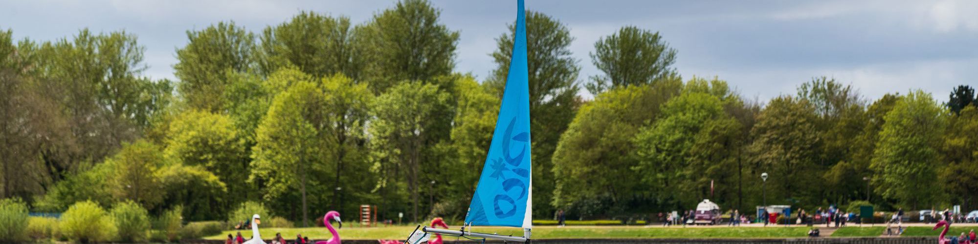 Person sailing on Willen Lake with pedalos in the background
