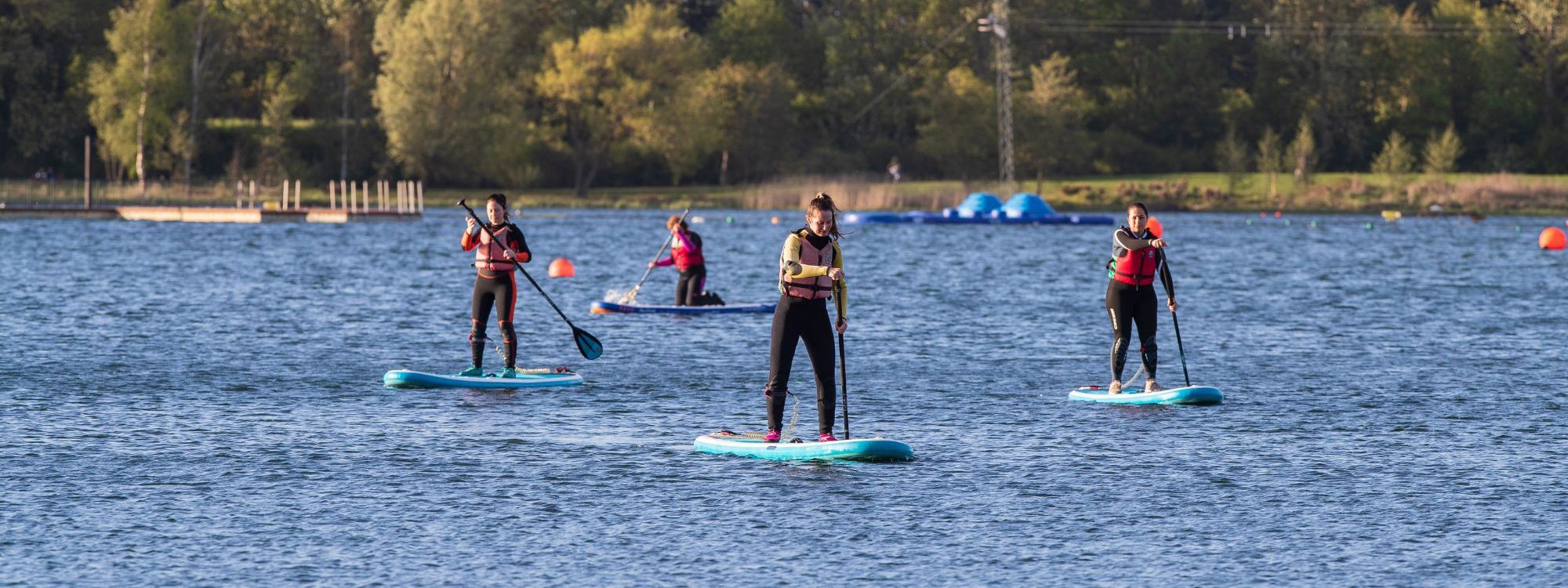 People standing on paddleboards on Willen Lake