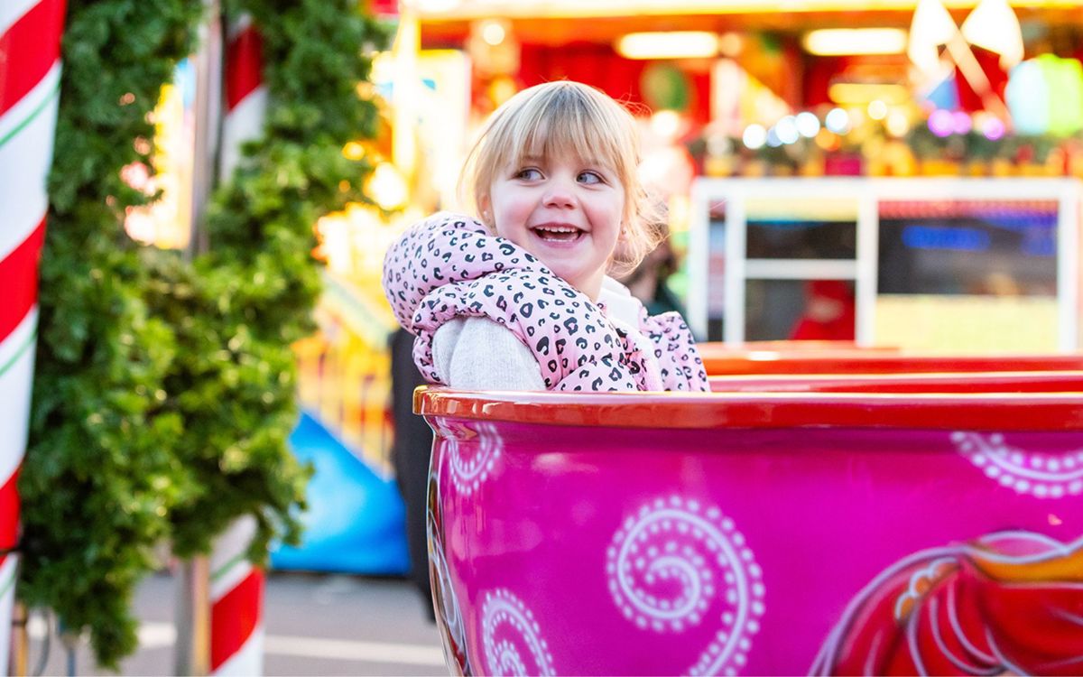 Child smiling on tea cup ride