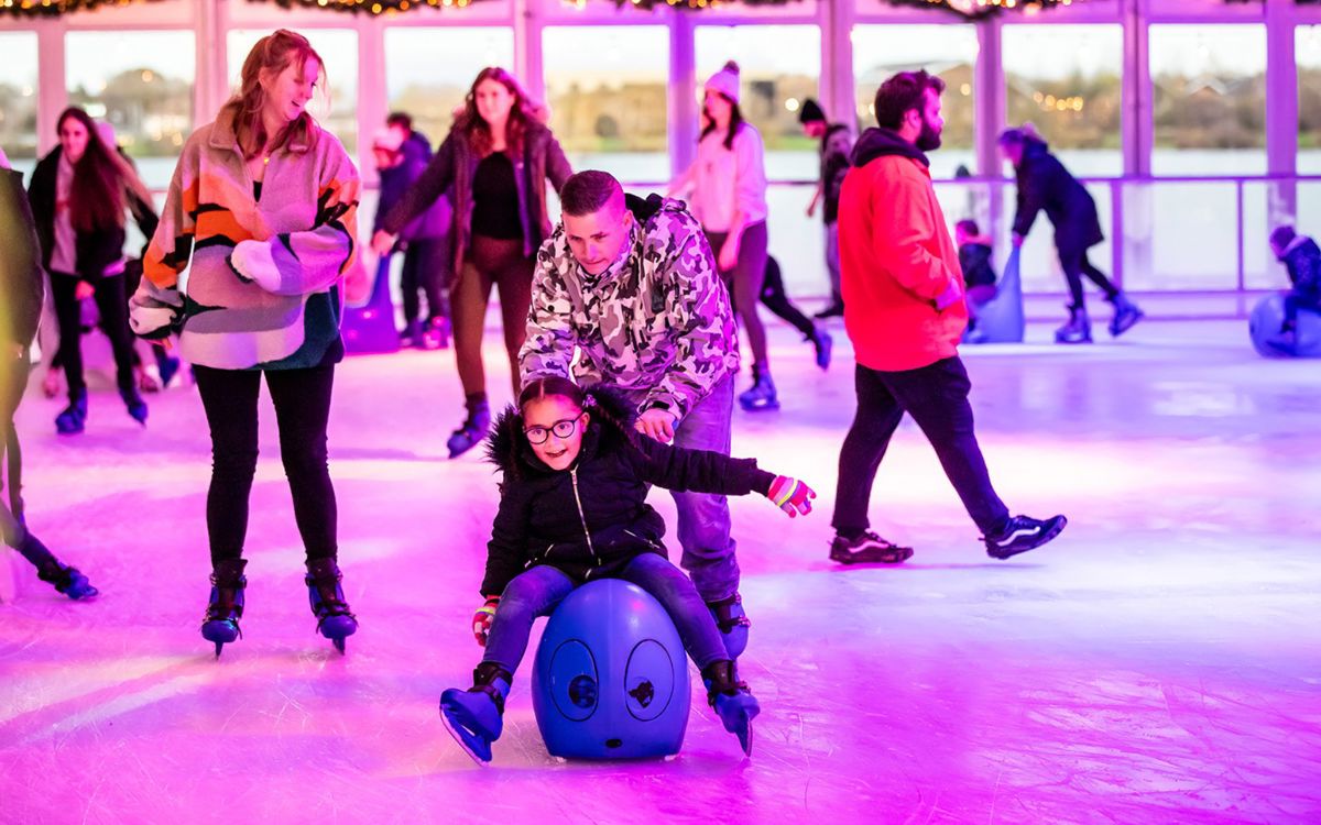 Parenting pushing child on skating aid at Willen On Ice