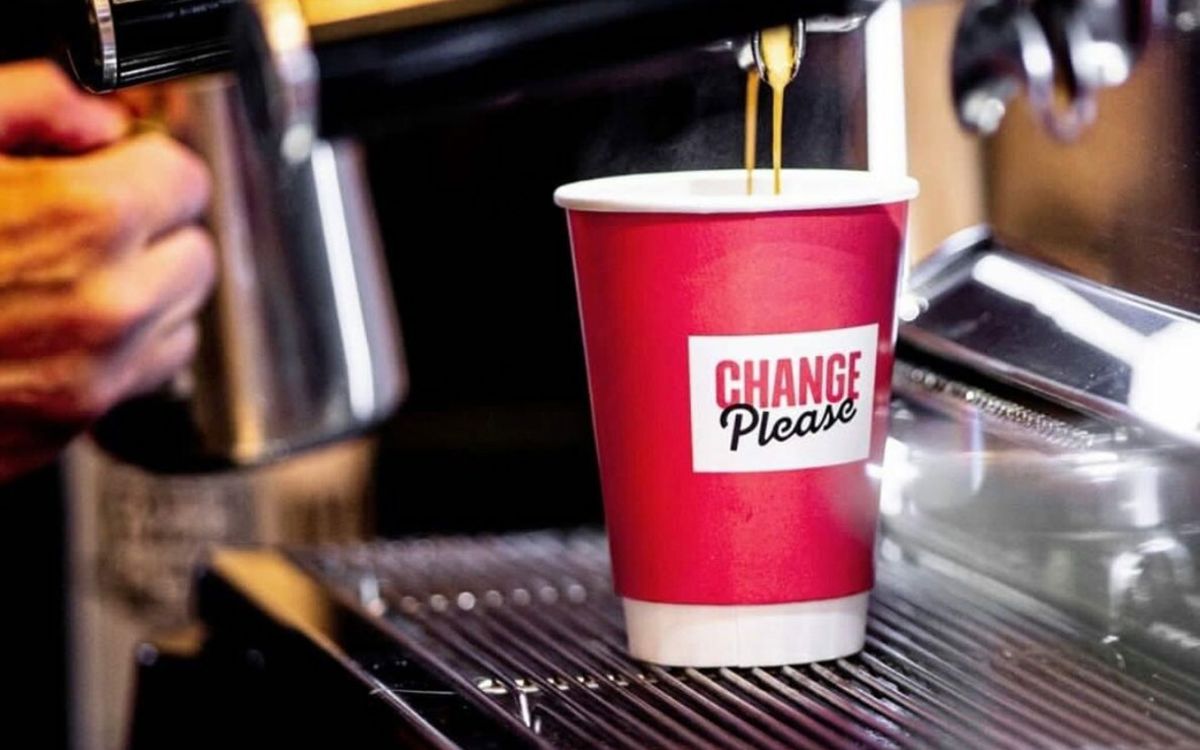 Cup with Change Please logo under dripping coffee machine