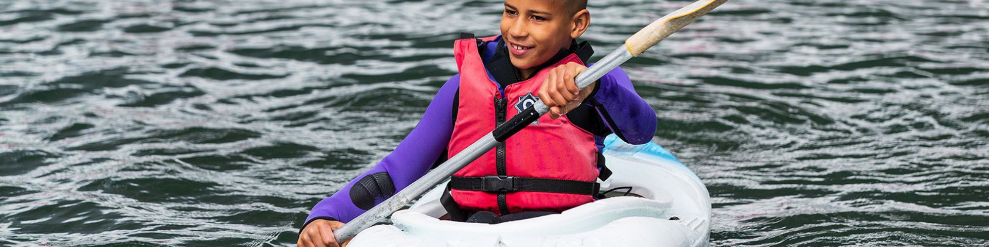 Person kayaking with paddle on Willen Lake in Milton Keynes