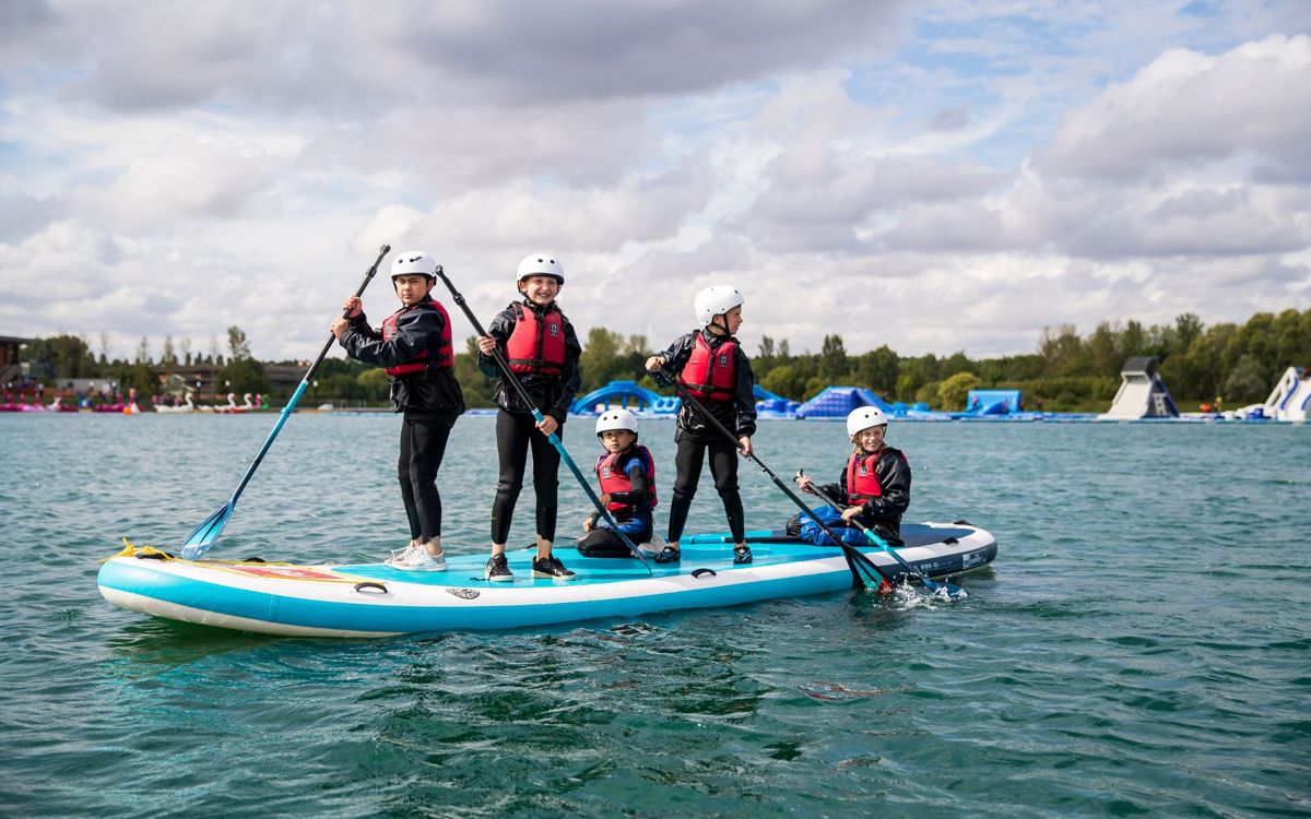 Group of children holding paddles on SUP board