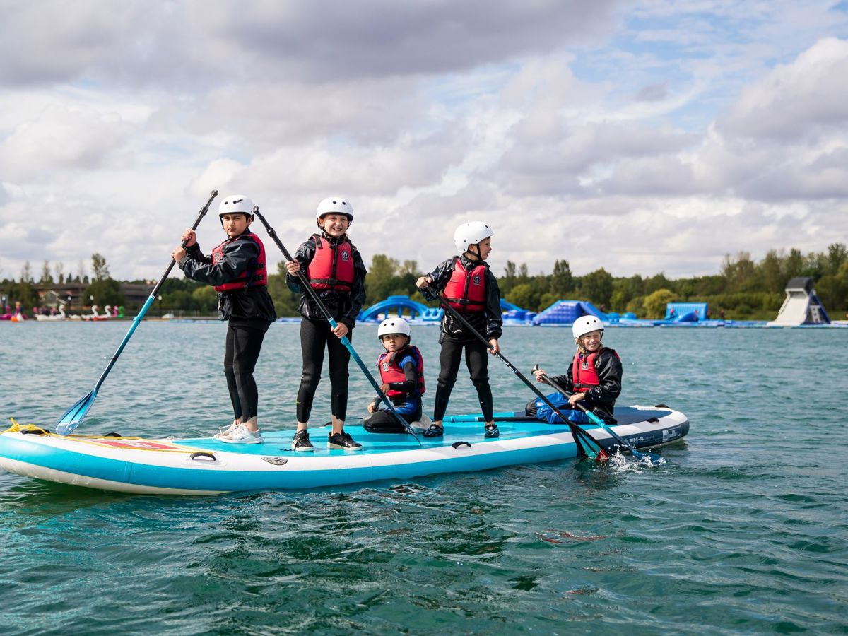 Group of children holding paddles on SUP board