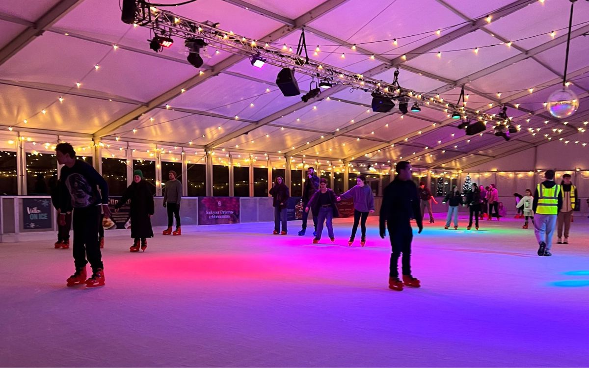 People ice skating on rink with lighting